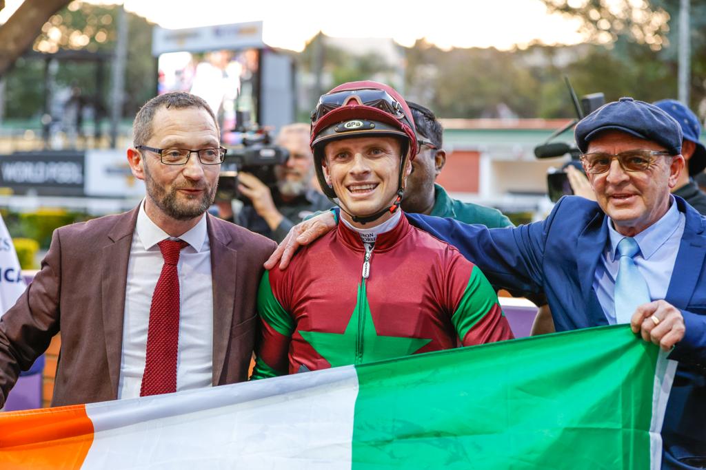 Fabulous firsts! Irish owner Michael Moroney, Lyle Hewitson and Carl Hewitson with the Irish flag on Hollywoodbets Durban July day 2023 – Lyle rode his Dad’s first feature winner and Mr Moroney’s first SA winner